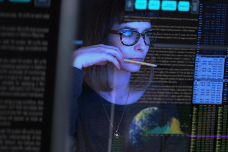 Reflection of a woman looking at a computer screen